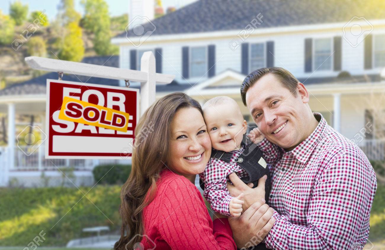 Young family in front of sole home sign