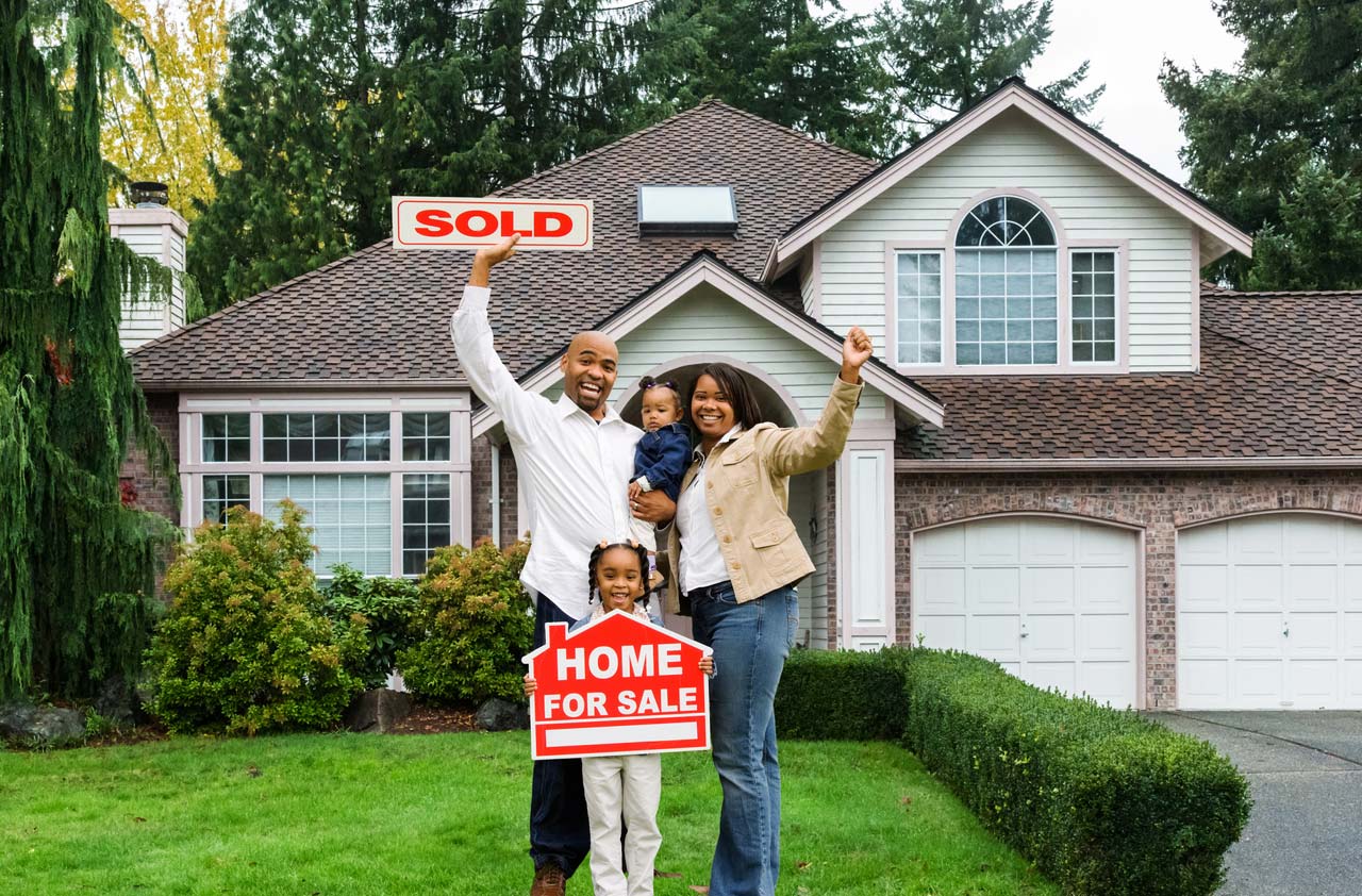 Family in front of home holding sold sign