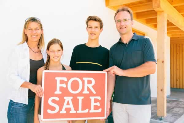 Family behind home for sale sign