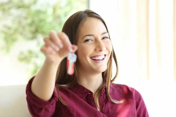 Single woman holding keys in front of home