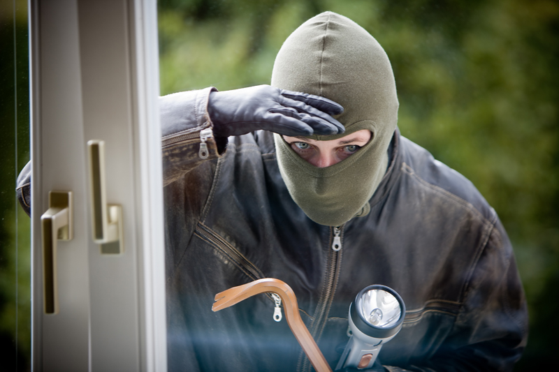 Masked burglar looking through door