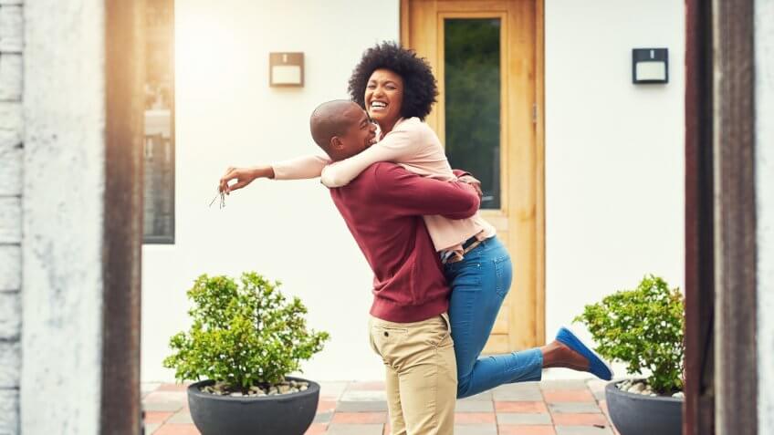 Happy couple hugging in front of home
