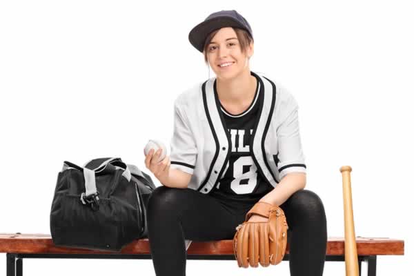 Girl in baseball uniform sitting on bench
